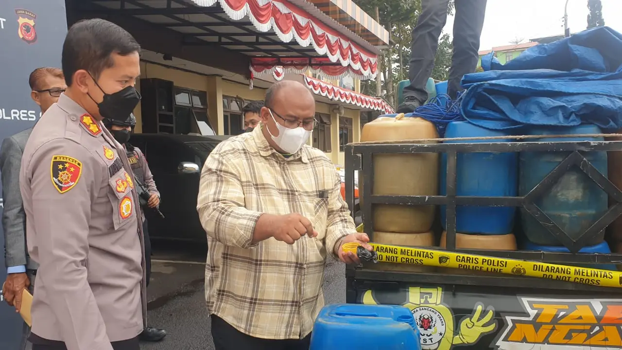 Kapolres Garut AKBP Wirdhanto Hadicaksono bersama Kasatreskrim AKP Dede Sopandi menunjukan barang bukti puluhan jerigen BBM bersubsidi hasil pengungkapan kasus. (Liputan6.com/Jayadi Supriadin)