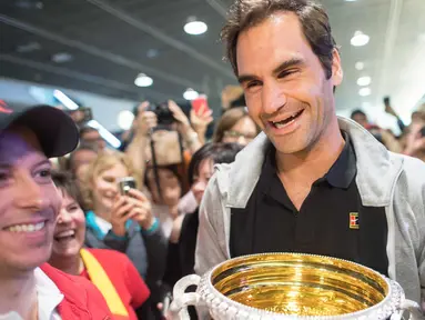 Petenis Swiss Roger Federer membawa trofi Australia Terbuka saat disambut penggemar di Bandara Zurich, di Kloten, Swiss, (30/1). Federer memenangkan final tunggal putramelawan petenis Kroasia Marin Cilic. (Ennio Leanza/Keystone via AP)