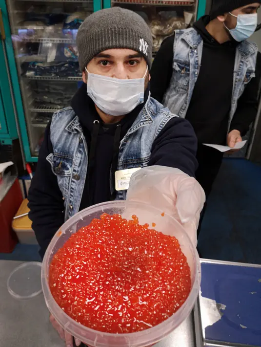Pedagang menawarkan telur ikan salmon atau kaviar merah di sebuah pasar, Moskow, Rusia, 22 November 2021. Warga Rusia yang ingin menikmati liburan musim dingin tradisional mereka dengan kaviar merah akan kecewa tahun ini, menyusul harga mencapai rekor tertinggi dalam sejarah. (Alexander NEMENOV/AFP)