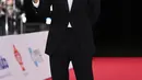 Song Joong Ki tampil gagah dengan setelan jas dan celana panjang hitam. Kemeja putih dilengkapi dengan dasi kupu-kupu hitam menyempurnakan penampilannya secara keseluruhan. [Foto: soompi.com]