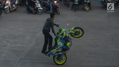 Seorang bikers melakukan aksi freestyle dengan motor di kawasan Kanal Banjir Timur, Jakarta, Selasa (29/5).Sekelompok pemuda di kawasan itu memanfaatkan waktu menunggu berbuka dengan melakukan atraksi freestyle yang mendebarkan. (Merdeka.com/Imam Buhori)
