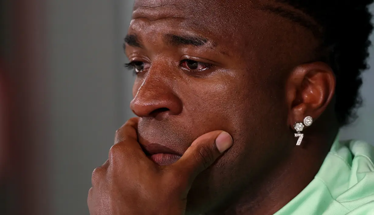 Ekspresi sedih pemain Brasil, Vinicius Jr saat konferensi pers menjelang laga persahabatan melawan Spanyol di tempat latihan Ciudad Real Madrid di Valdebebas, pinggiran Madrid, pada 25 Maret 2024. Laga tersebut memiliki slogan "Satu Kulit" untuk membantu memerangi rasisme. (AFP/Pierre-Philippe Marcou)