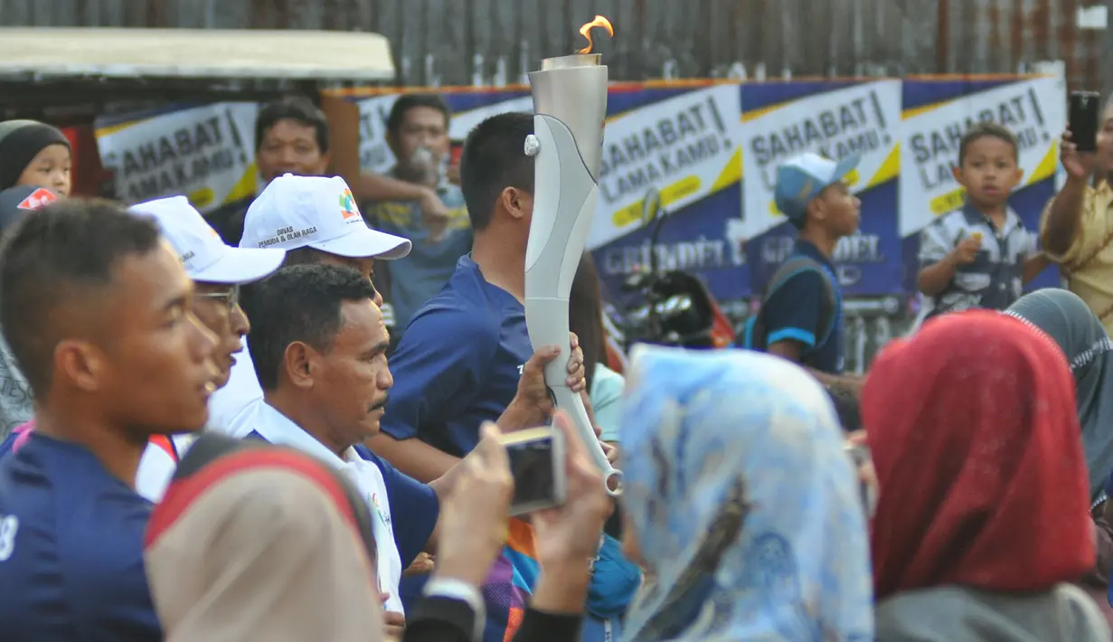 Petinju legendaris Indonesia, Nico Thomas, membawa obor Asian Games XVIII saat melintasi di Kota Malang, Jawa Timur, Jumat (20/7/2018). Sebanyak 10 kota di Indonesia akan dilalui oleh obor Asian Games. (Bola.com/Iwan Setiawan)