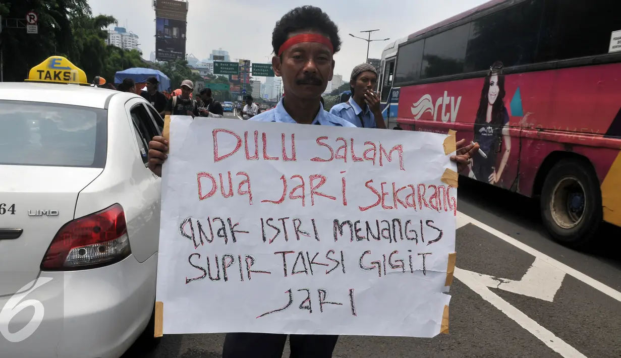 Seorang Supir Taksi membawa spanduk saat demo di depan Gedung DPR/MPR, Jakarta, Selasa (22/3/2016). Selain melakukan demo, supir taksi tersebut melakukan sweeping ke supir taksi yang beroperasi di dalam tol dan membakar ban. (Liputan6.com/Johan Tallo)