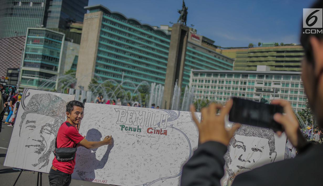 Masyarakat menandatangani dilukisan capres 01 dan 02  yang bertema ‘ Pemilu Penuh Cinta’  saat Car Free day di kawasan Bundaran HI, Jakarta, MInggu (14/4). Kampanye tersebut untuk mengajak masyarakat untuk berpartisipasi dalam Pemilu secara Damai. (Liputan6.com/Faizal Fanani)