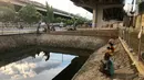 Sejumlah warga memancing ikan di kubangan yang berada di Jalan DI Panjaitan, Jatinegara, Jakarta, Selasa (16/6/2020). Meski telah dipagari, sejumlah warga tetap memancing ikan di lokasi yang merupakan saluran pembuangan tersebut. (Liputan6.com/Immanuel Antonius)