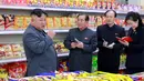 Pemimpin Korea Utara, Kim Jong-un berbincang dengan stafnya ketika berada di toko makanan saat mengunjungi Taesong Department Store setelah dibuka untuk umum di Korea Utara (8/4). (KCNA VIA AFP Photo)