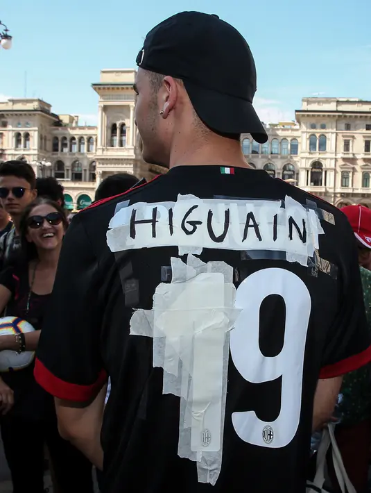 Seorang tifosi AC Milan mengenakan jersey bernama Higuain sebelum kedatangan pemain Argentina tersebut di alun-alun pusat Milan Piazza Duomo (3/8). Higuain akan membela I Rossoneri hingga 30 Juni 2019 dengan status pinjaman. (AFP Photo/Stringer)