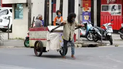 Pemulung melintas di Jalan Raden Saleh, Jakarta, Kamis (30/4/2020). Setiap Ramadan tiba, kemunculan pemulung yang membawa gerobak marak terjadi. Saat ini, kemunculan mereka menjadi masalah tersendiri di tengah upaya memutus mata rantai penyebaran Covid-19. (Liputan6.com/Helmi Fithriansyah)