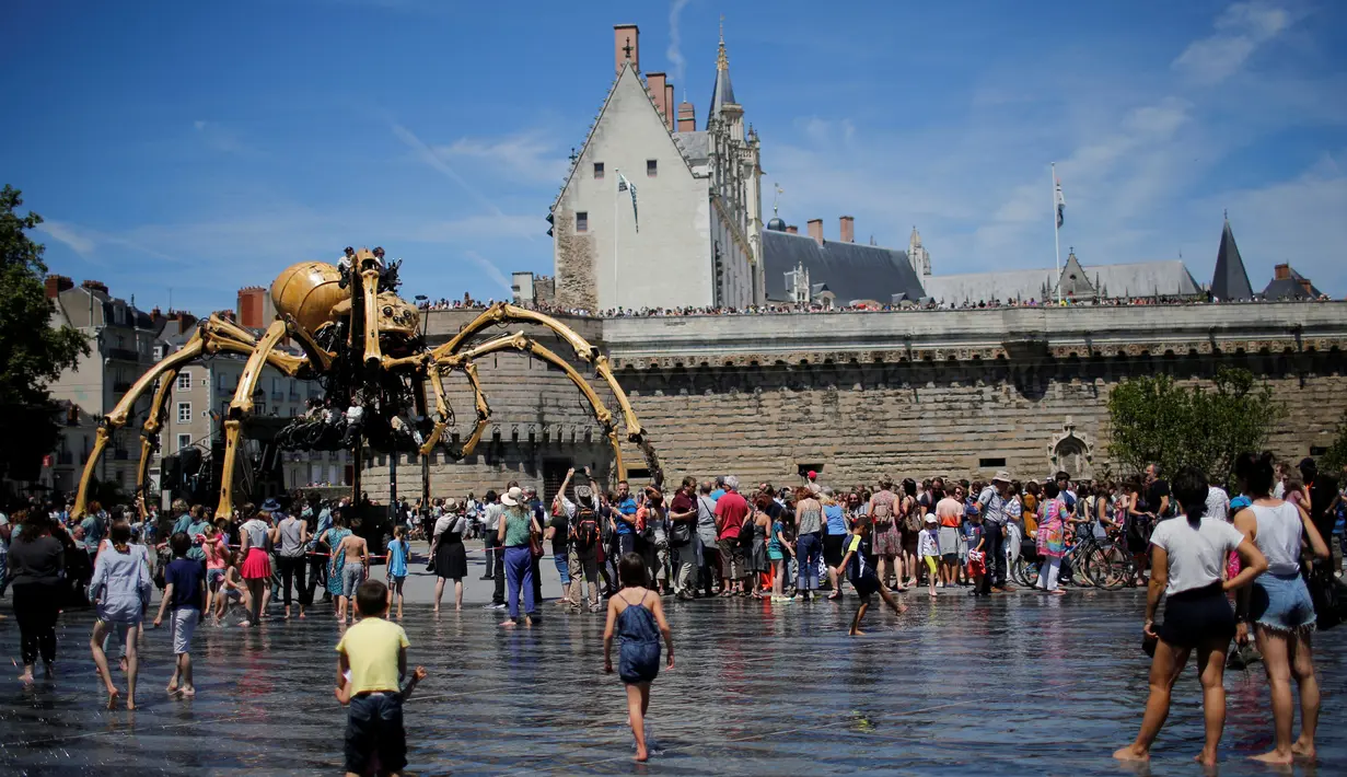Sejumlah orang melihat robot mekanik laba-laba raksasa bernama Kumo Ni saat berjalan berkeliling Kota Nantes, Prancis, Jumat (8/7). Robot Mekanik laba-laba raksasa ini di buat oleh perusahaan La Machine. (REUTERS/Stephane Mahe)
