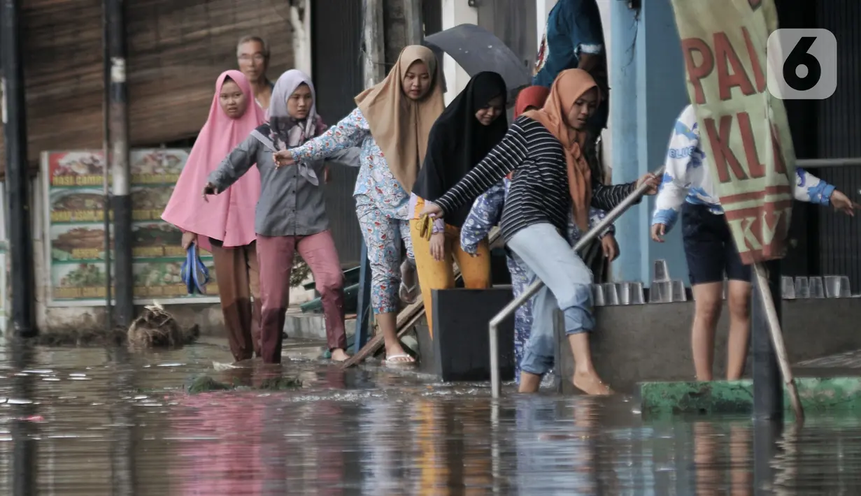 Warga melintasi banjir yang merendam Jalan RA Kartini, Bekasi, Jawa Barat, Kamis (2/1/2020). Banjir yang merendam Jalan RA Kartini sejak kemarin melumpuhkan akses kendaraan dan perekonomian warga setempat. (merdeka.com/Iqbal Nugroho)
