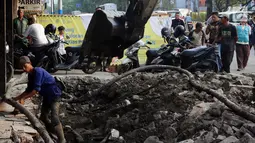 Pekerja dibantu alat berat membongkar saluran air yang akan diperbaiki di jalan Hayam Wuruk, Jakarta, Selasa (20/11). Perbaikan dan pelebaran saluran air ini untuk mengantisipasi terjadinya banjir di kawasan tersebut saat hujan. (Liputan6.com/Johan Tallo)