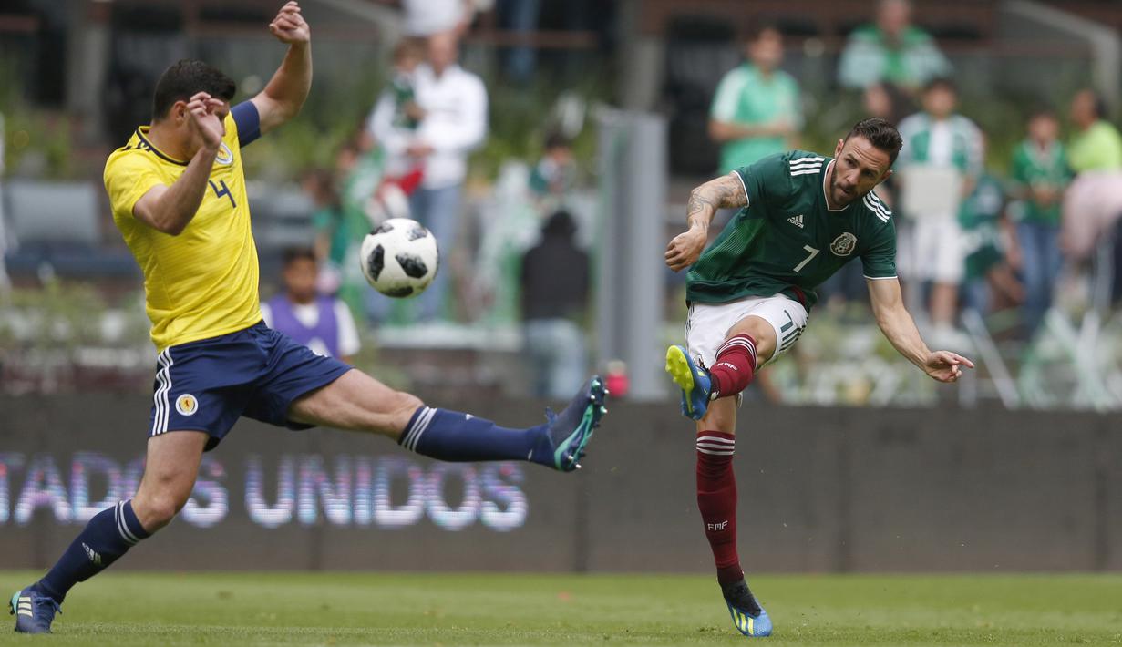Pemain Meksiko, Miguel Layun (kanan) melepaskan tembakan ke gawang Skotlandia pada laga uji coba di Azteca Stadium, Meksiko City, (2/6/2018). Meksiko menang 1-0.  (AP/Rebecca Blackwell)