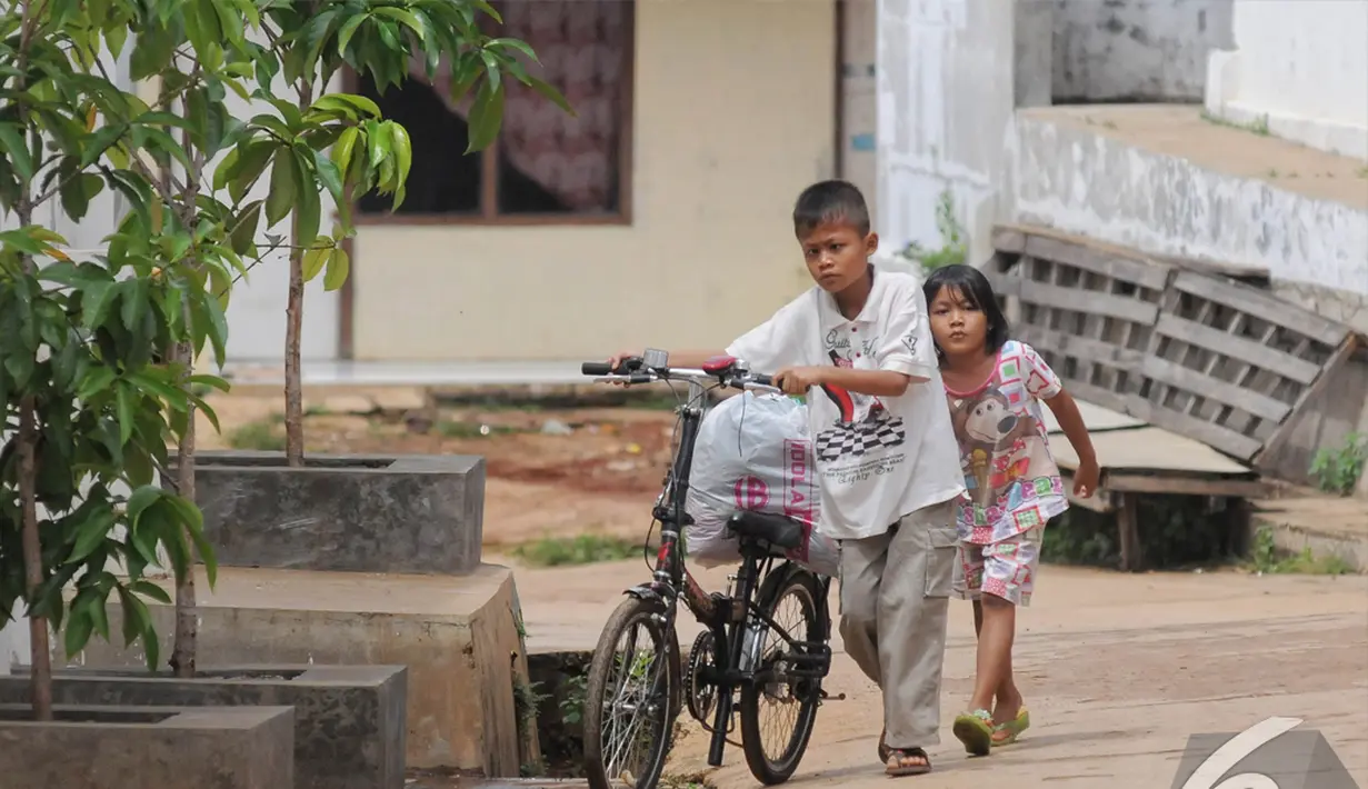 Sony Wakwaw bersama adiknya membawa beberapa barang dengan sepeda saat pindah kerumah barunya di kawasan Cibubur, Jakarta Timur. Foto diambil pada Kamis (4/12/2014). (Liputan6.com/Herman Zakharia)