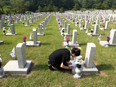 Warga Korea Selatan, Oh Myung-Soon menangis di depan batu nisan saudaranya yang meninggal selama Perang Korea di pemakaman nasional, Seoul, Korea Selatan, Rabu (6/6). Kegiatan ini dilakukan dalam Memorial Day. (AP Photo/Ahn Young-joon)