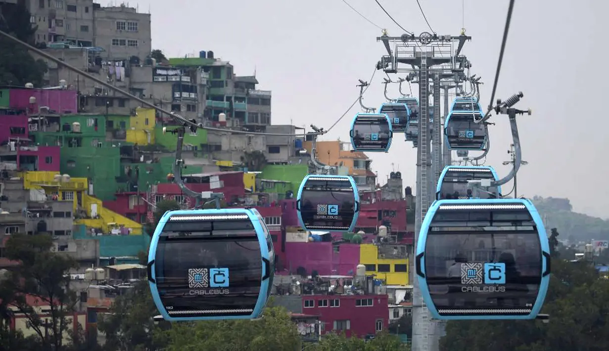 Penumpang melakukan perjalanan dengan sistem kereta gantung yang dijuluki Cablebus setelah peresmiannya di pinggiran Mexico City, Meksiko, 12 Juli 2021. Sistem kereta gantung ini memudahkan penumpang untuk melakukan perjalanan dari Cuautepec menuju pusat kota. (PEDRO PARDO/AFP)