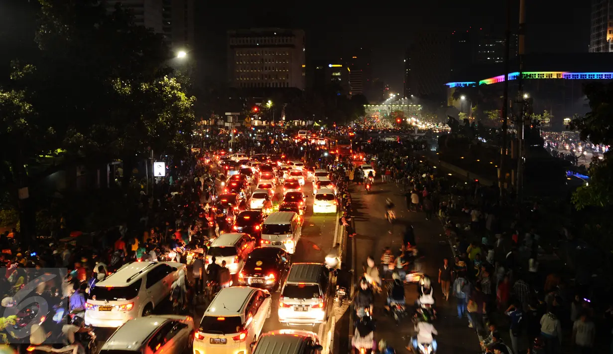 Pengendara antre untuk melewati kawasan Jalan Medan Merdeka Barat, Jakarta, Minggu (1/1). Ribuan warga merayakan malam pergantian tahun di sekitar kawasan Monas dan bundaran air mancur. (Liputan6.com/Helmi Fithriansyah)