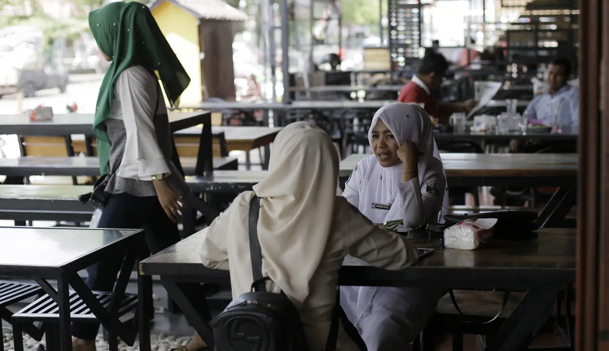 Pengunjung duduk di sebuah restoran di Bireuen, Aceh, Rabu (5/9). Selain larangan duduk bersama nonmuhrim, Pemerintah Kabupaten Bireuen juga melarang pramusaji melayani perempuan di atas pukul 21.00 WIB, kecuali dengan muhrimnya (AFP PHOTO/AMANDA JUFRIAN)