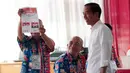 Capres nomor urut 01 Joko Widodo atau Jokowi melihat petugas KPPS yang menunjukkan kertas suara saat melakukan pencoblosan dalam Pemilu 2019 di TPS 008 Gambir, Jakarta Pusat, Rabu (17/4). Jokowi dan Iriana terdaftar di nomor urut 154 dan 155 daftar DPT. (AP/Dita Alangkara)