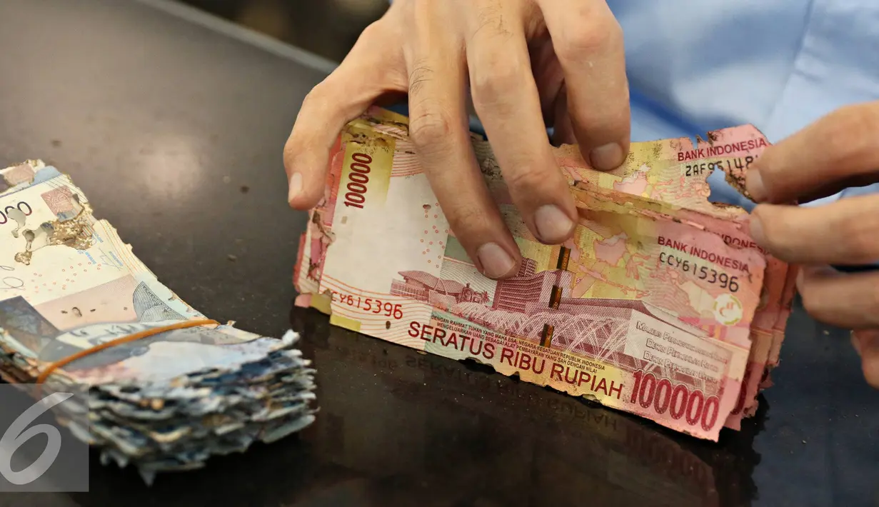 Petugas mengecek uang rusak yang ditukarkan di Bank Indonesia, Jakarta, Senin (6/6). BI meminta masyarakat menukarkan uang yang sudah tidak layak edar dengan uang baru agar uang yang beredar tetap berkualitas tinggi. (Liputan6.com/Immanue Antonius)