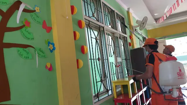Personel PPSU membersihkan pagar Taman Belajar Asmaul Husna, Petukangan Utara dengan cairan disinfektan. (Liputan6.com/Luqman Rimadi)