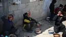 Situasi semakin memburuk ketika sejumlah lembaga bantuan mengurangi distribusi pasokan bahan pangan. World Central Kitchen disebut-sebut menghentikan pasokan tepung harian sebesar 20 hingga 30 ton. Tampak dalam foto, anak-anak pengungsi Palestina memakan makanan yang mereka terima dari dapur amal di kamp pengungsi Nuseirat, Jalur Gaza Tengah pada 13 April 2026. (Eyad Baba/AFP)