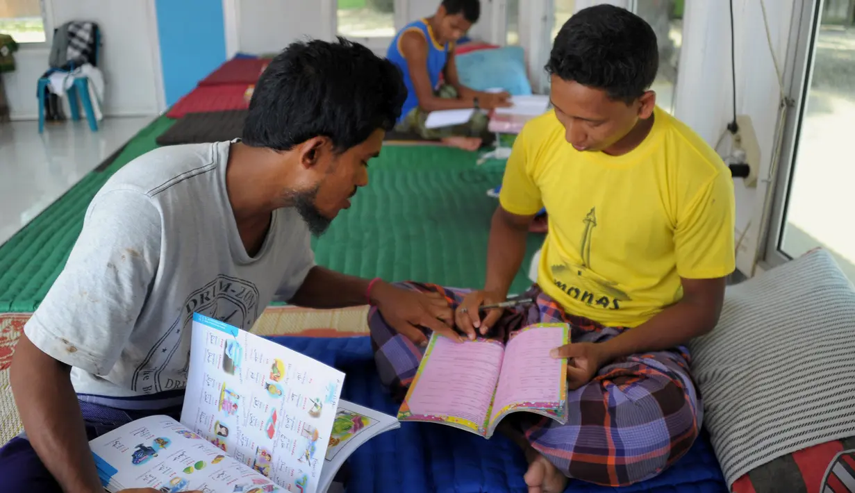 Para pengungsi Rohingya tampak asik membaca buku di penampungan sementara Blang Adoe, Aceh Utara, Aceh, Rabu (27/4). Pengungsi masih menunggu kejelasan nasib mereka sebelum batas waktu keberadaan mereka di Indonesia. (Chaideer Mahyuddin / AFP)