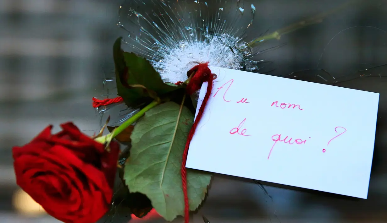 Bunga Mawar ditancapkan pada lubang jendela yang pecah akibat serangan penembakan yang terjadi di di Paris, Prancis, Sabtu (14/11/2015). Dikabarkan ratusan orang tewas dalam serangan ini. (REUTERS/Christian Hartman)