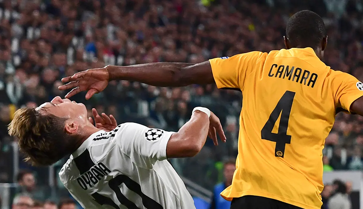 Pemain Young Boys, Mohamed Aly Camara (kanan) memukul pemain Juventus Paulo Dybala saat bertanding dalam di Grup H Liga Champions, Stadion Allianz, Turin, Italia, Selasa (2/10). Juventus membungkam Young Boys 3-0 lewat hattrick Dybala. (Miguel MEDINA/AFP)