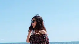 Gayanya kini semakin menawan. Seperti saat dirinya tampak bersantai di pantai. Meski memakai outif off shoulder dan rok hitam panjang. Dirinya tetap cantik dan menawan, ditambah kacamata hitam. (Liputan6.com/IG/@sisisinta)