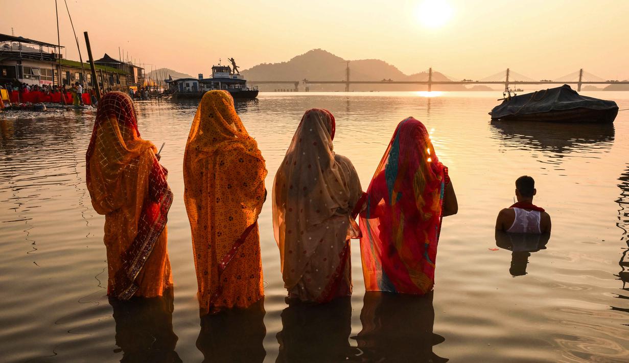 Umat Hindu memanjatkan doa kepada Dewa Matahari pada perayaan 'Chhath Puja' di tepi Sungai Brahmaputra di Guwahati pada Senin 27 Oktober 2025. (Biju BORO/AFP)