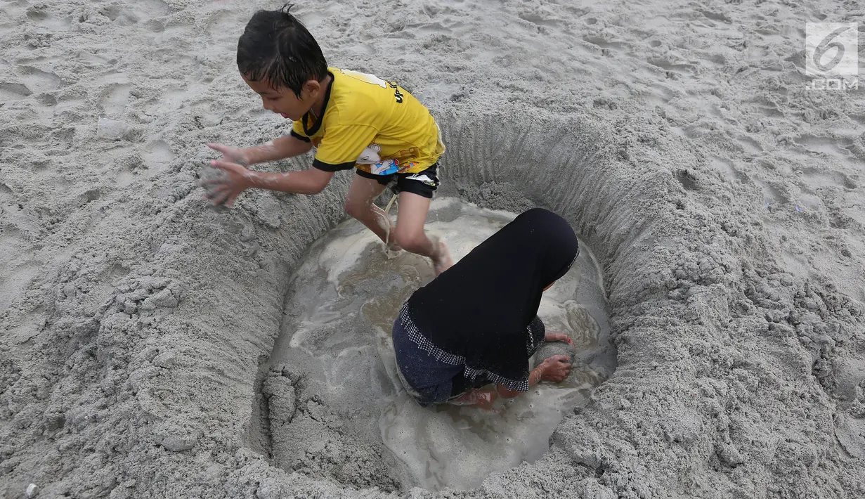 Anak-anak bermain pasir di Pantai Ancol, Jakarta, Senin (26/6). Memasuki hari kedua lebaran Warga memanfaatkan liburnya bersama keluarga bertamasya ke tempat-tempat wisata yang ada di Jakarta kususnya Ancol. (Liputan6.com/Johan Tallo)