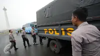 Petugas kepolisian menaiki truk pengangkut saat melakukan pengamanan di kawasan Monas, Jakarta, Selasa (18/4). Polda Metro Jaya dan Kodam Jaya mengerahkan 64.523 personel gabungan untuk mengawal Pilkada DKI 2017 putaran kedua. (Liputan6.com/Faizal Fanani)