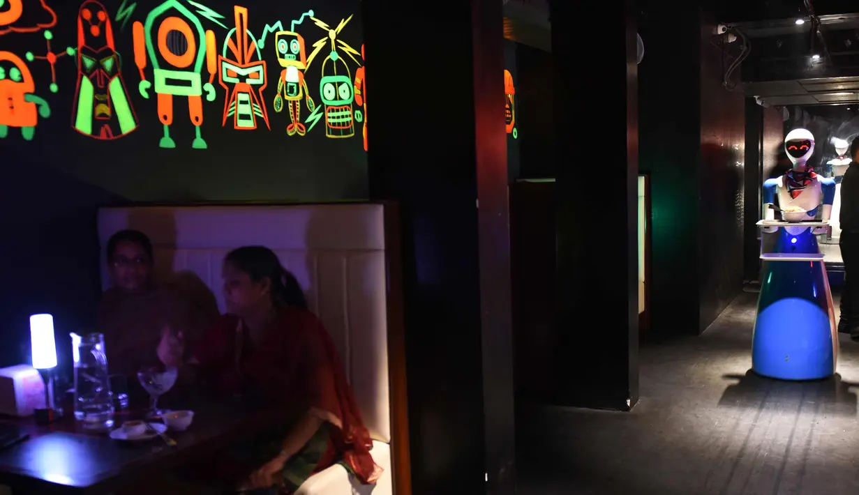 Pengunjung menunggu hidangan yang  dibawa pelayan robot di Chennai, India (20/12). Restoran ini merupakan yang pertama di India yang memiliki pelayan robot dengan server otomatis membawa piring dari dapur ke pelanggan. (AFP Photo/Arun Sankar)