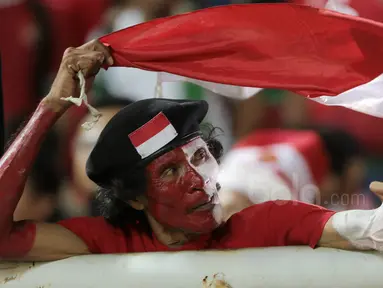 Seorang suporter Timnas Indonesia mengibarkan bendera Merah-Putih saat mendukung tim Garuda melawan Vietnam pada laga Semifinal AFF Cup 2016 di Stadion Pakansari, Bogor, (03/12/2016). (Bola.com/Nicklas Hanoatubun)