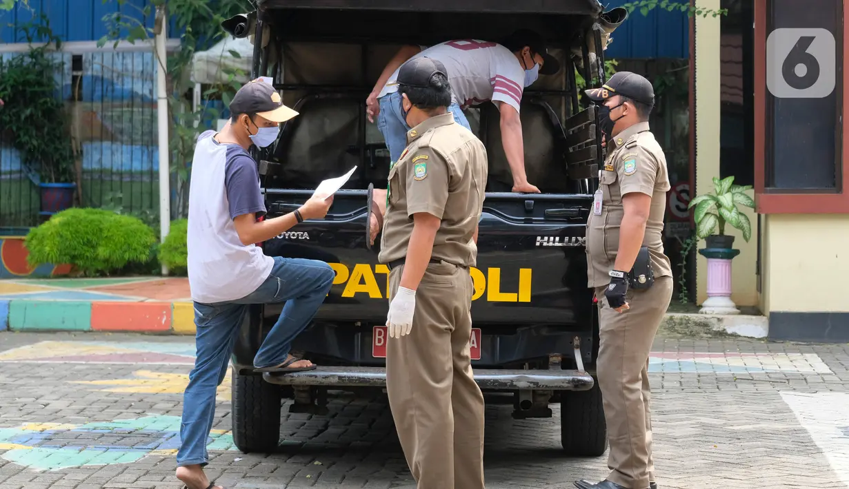 Warga pelanggar PSBB diangkut mobil Satpol PP di Tangerang, Kamis (14/5/2020). Pemkot Tangerang melakukan tindakan bagi pelanggar PSBB seperti tidak menggunakan masker dengan membawa mereka ke kantor Kecamatan Karawaci Baru untuk dilakukan pemeriksaan Rapid Test COVID-19. (Liputan6.com/Angga Yuniar)