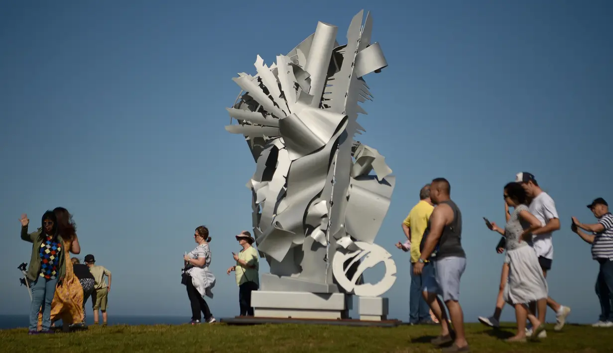 Pengunjung berjalan dekat sebuah patung bagian dari pameran Sculpture by the Sea di Sydney, Australia, Jumat (19/10). Dalam pameran ini, tak kurang dari 100 patung dengan berbagai ukuran dan bentuk menghiasi sepanjang bibir pantai. (PETER PARKS/AFP)