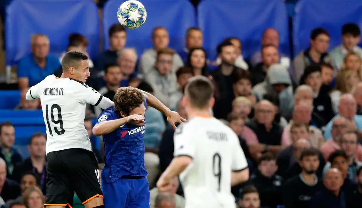 Pemain Valencia Rodrigo Moreno melompat saat berebut bola dengan  bek kiri Chelsea, Marcos Alonso pada laga perdana Grup H Liga Champions melawan Valencia  di Stamford Bridge, Rabu (18/9/2019). Chelsea takluk 0-1 di tangan Valencia. (AP Photo/Frank Augstein)
