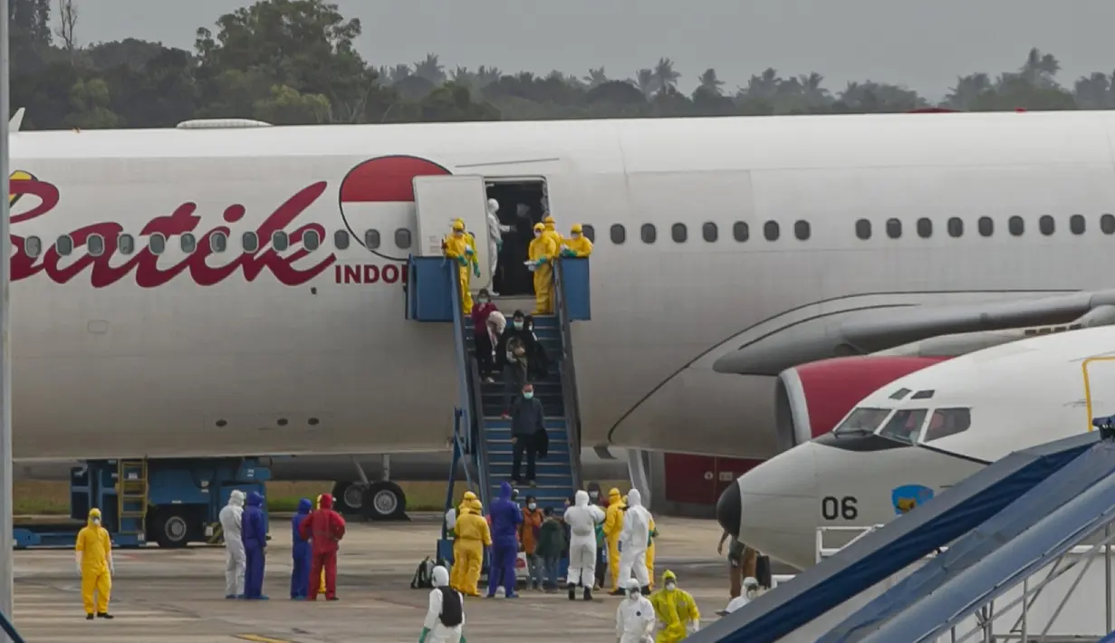 Sejumlah Warga Negara Indonesia (WNI) yang dievakuasi dari Wuhan, China keluar dari pesawat  Batik Air di bandara internasional Hang Nadim, Batam, Minggu (2/2/2020). Sebanyak 245 WNI di Wuhan dievakuasi ke Indonesia terkait merebaknya virus corona di kota tersebut. (AP Photo/Luth Panjalu)