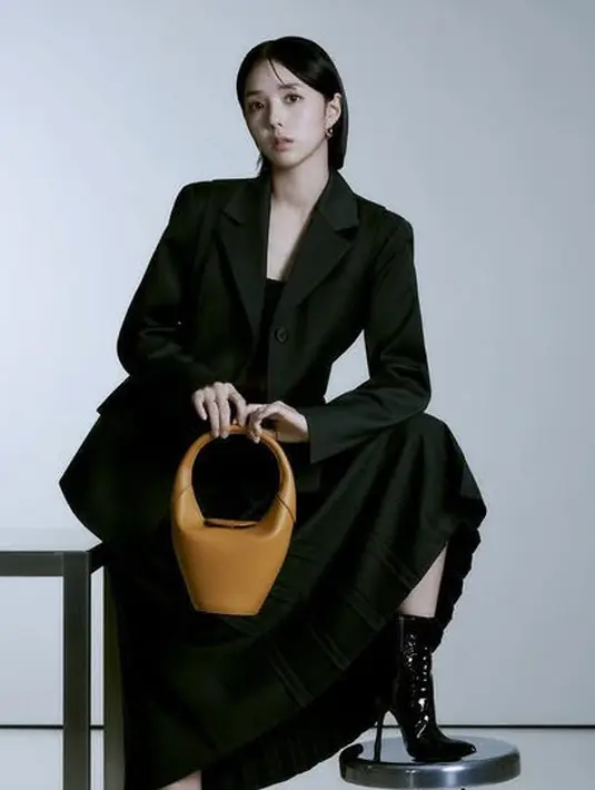 Ia juga mengenakan blazer hitam dengan inner tube senada dengan rok panjang. Ia memadukannya dengan boots heels sambil membawa handbag coklat. [@soobinms]