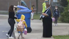 Seorang guru yang memakai masker (kanan) menyapa murid di luar sekolah di Mississauga, Ontario, Kanada (9/9/2020). Beberapa sekolah di Ontario dibuka kembali pada Rabu (9/9), menawarkan kombinasi kelas tatap muka dan pembelajaran daring (online) bagi para murid. (Xinhua/Zou Zheng)