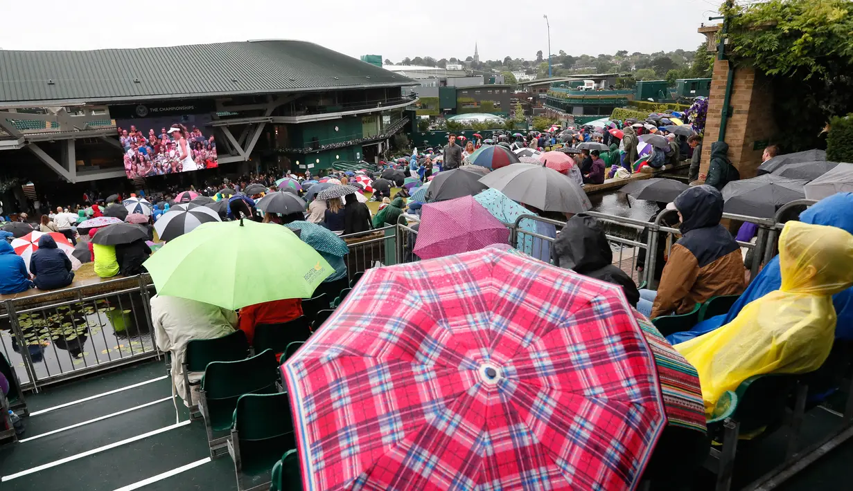 Para penonton memakai payung saat menyaksikan perempat final tunggal wanita antara Simona Halep asal Romania dan petenis Inggris Johanna Konta di sebuah layar lebar pada kejuaraan tenis Wimbledon 2017 di London (11/7). (AP Photo/Kirsty Wigglesworth)