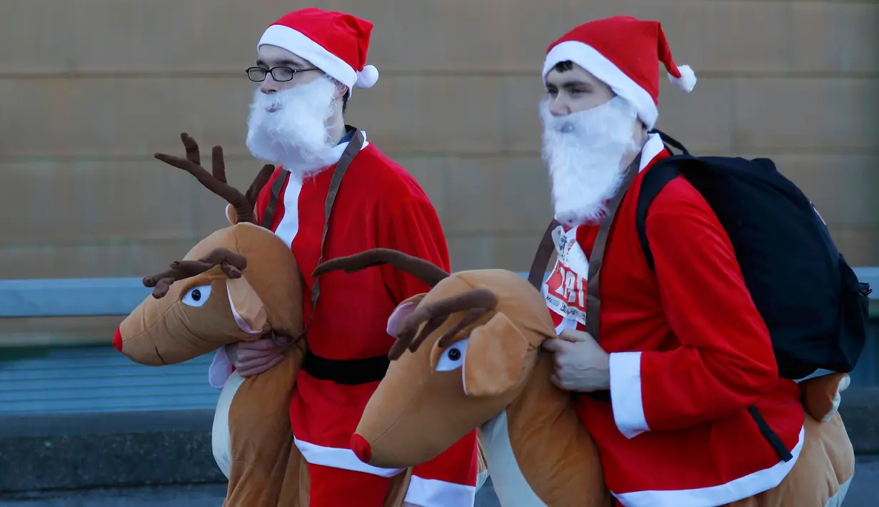 Dua orang pria yang mengenakan kostum Santa Claus lengkap dengan boneka rusa mengikuti balap lari Santa Dash di Liverpool, Inggris, Minggu (4/12). (Reuters/Phil Noble)
