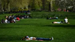 Seorang wanita tampak berjemur di sebuah taman di pusat kota London,  Inggris, Minggu (9/4). Sinar matahari hangat bersuhu 20 derajat celsius dimanfaatkan warga Inggris untuk berjemur di taman-taman kota. (AFP PHOTO / BEN STANSALL)