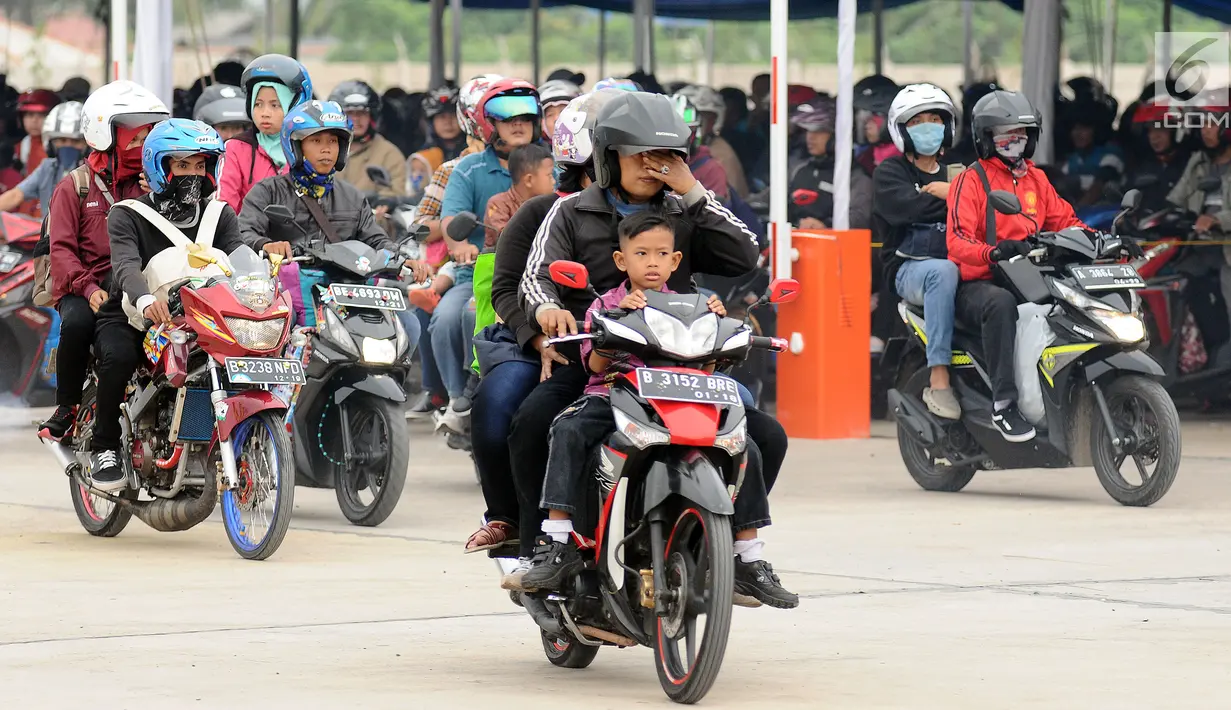 Pemudik membawa anaknya saat akan memasuki kapal penyereberangan di Dermaga 6 Pelabuhan Merak, Banten, Kamis (22/6). Meski berbahaya, sejumlah pemudik masih nekat membawa anak mereka dengan sepeda motor. (Liputan6.com/Helmi Fithriansyah)