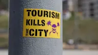 Stiker menentang pariwisata sebagai bagian dari protes anti-turis di Barcelona pada Mei 2017. (dok. PAU BARRENA / AFP)