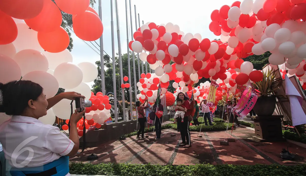 Sejumlah warga berfoto dengan balon berwarna merah putih yang menghiasi halaman Balai Kota, Jakarta, Senin (8/5). Balon-balon tersebut merupakan bentuk dukungan moril untuk Gubernur DKI Jakarta Basuki Tjahaja Purnama (Ahok). (Liputan6.com/Faizal Fanani)