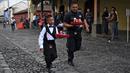 Pramusaji dan seorang anak beradu kecepatan sambil membawa nampan dalam Waiters Race ke-16 di Antigua, barat daya Ibu Kota Guatemala City, Rabu (14/11). Lomba ini diikuti oleh ratusan peserta yang merupakan pelayan restoran dan kafe. (JOHAN ORDONEZ/AFP)