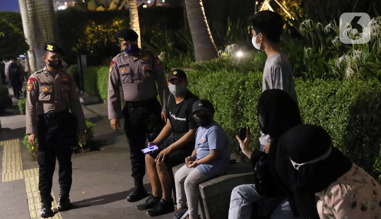 Polisi melakukan pembubaran terhadap warga yang berkerumun di kawasan Bundaran HI, Jakarta, Jumat (31/12/2021). Petugas gabungan melarang perayan malam pergantian tahun di wilayah Jakarta untuk mencegah penyebaran COVID-19. (Liputan6.com/Angga Yuniar)