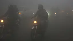 Kendaraan melaju dengan menyalakan lampu depan saat kabut tebal menyelimuti Lahore, Pakistan, 15 Desember 2021. Kabut tebal membuat kendaraan harus melaju lambat karena jarak pandang berkurang. (AP Photo/K.M. Chaudary)